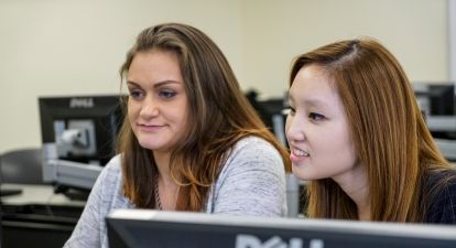Two female student workers at a computer.
